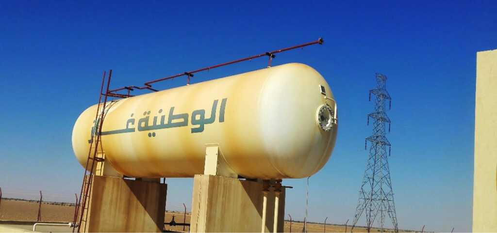 A horizontal strategic storage tank for liquefied petroleum gas (LPG) at Al Multaqa warehouse, mounted on sturdy concrete foundations, and the water sprinkler system for emergency cooling next to the high-pressure line towers is visible above.