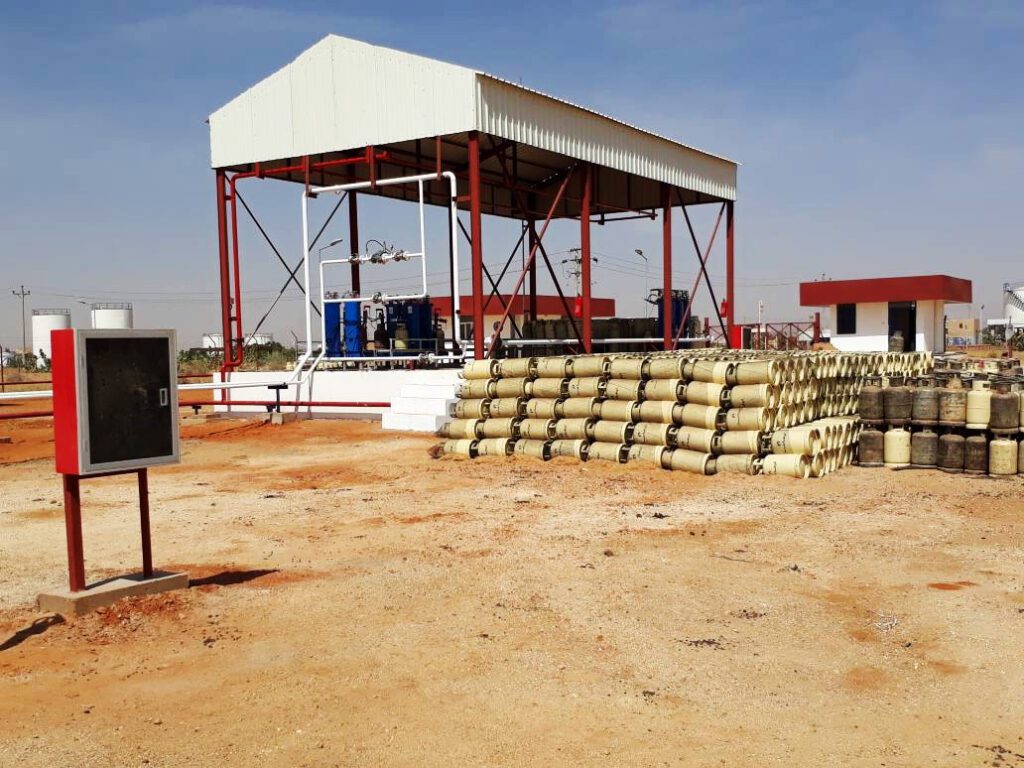 A general view of the gas facility showing the arrangement of gas cylinders ready for supply, with the processing units and administrative buildings of the distribution center visible in the background.