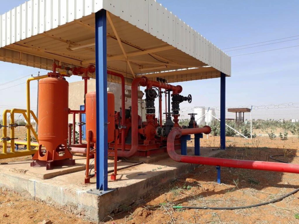 The central firefighting system, under a metal canopy, includes red emergency pumps and pressure tanks to ensure rapid response and protection of warehouse facilities.
