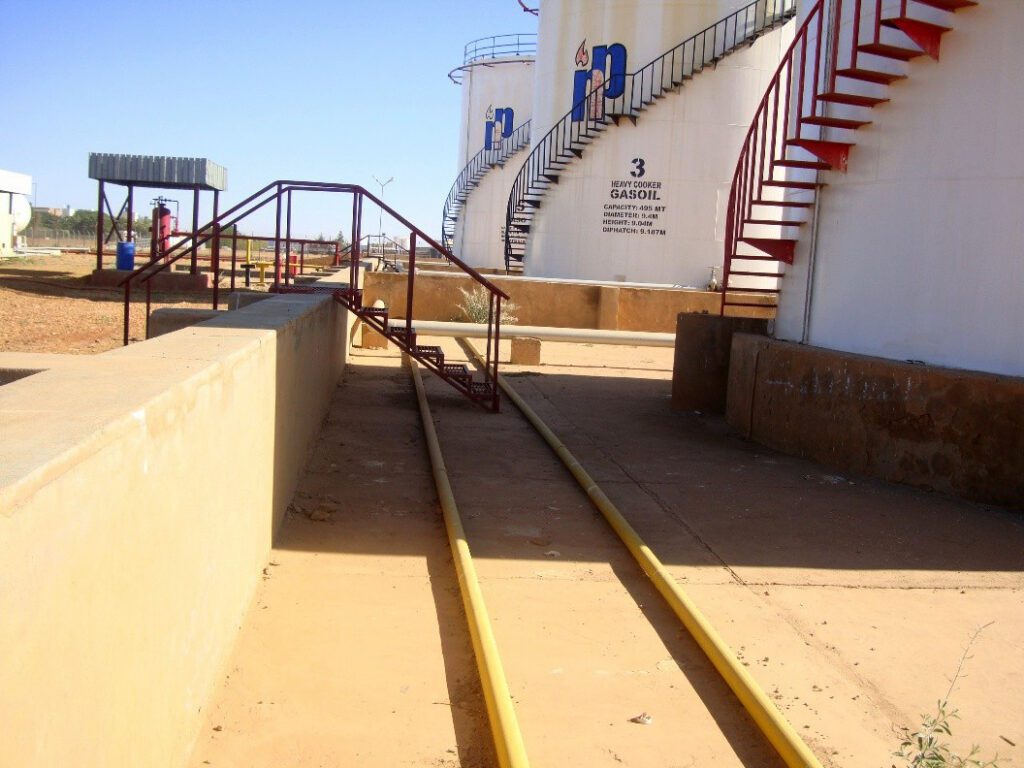 Technical service corridors between gasoil tanks, including parallel pipelines for transporting products and overhead access ladders, are designed in accordance with occupational safety standards in oil depots.